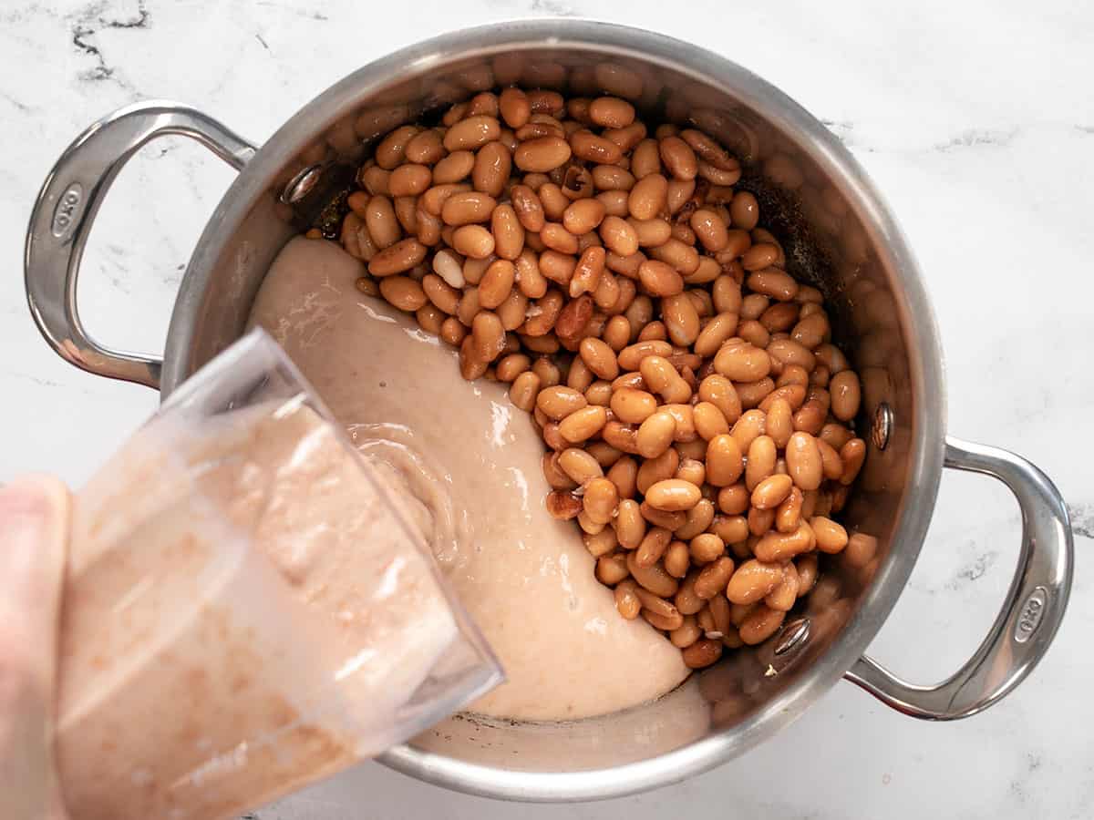 Whole beans in the pot and puréed beans being poured in. 