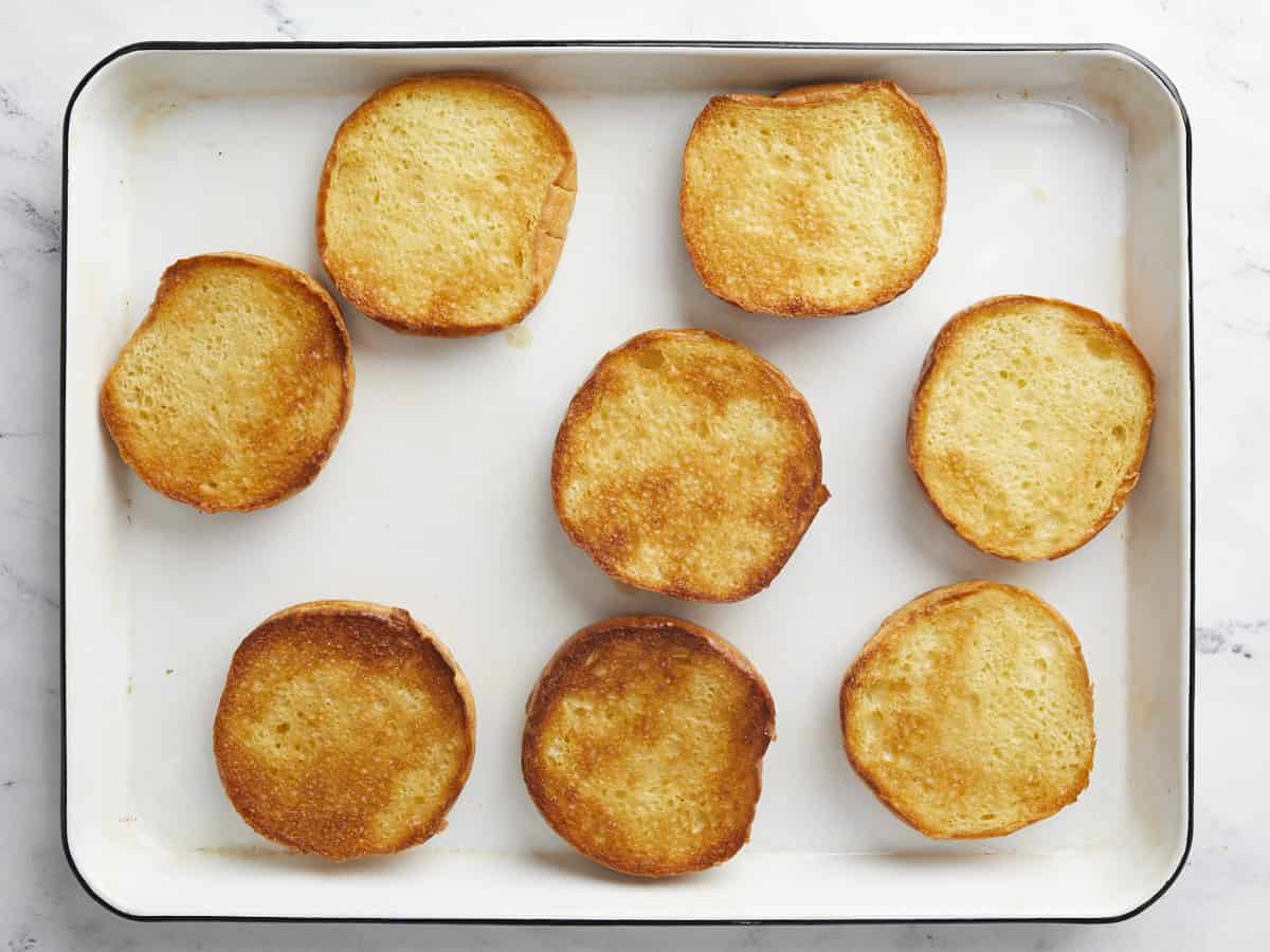 Overhead shot of toasted buttered buns in a sheet pan.