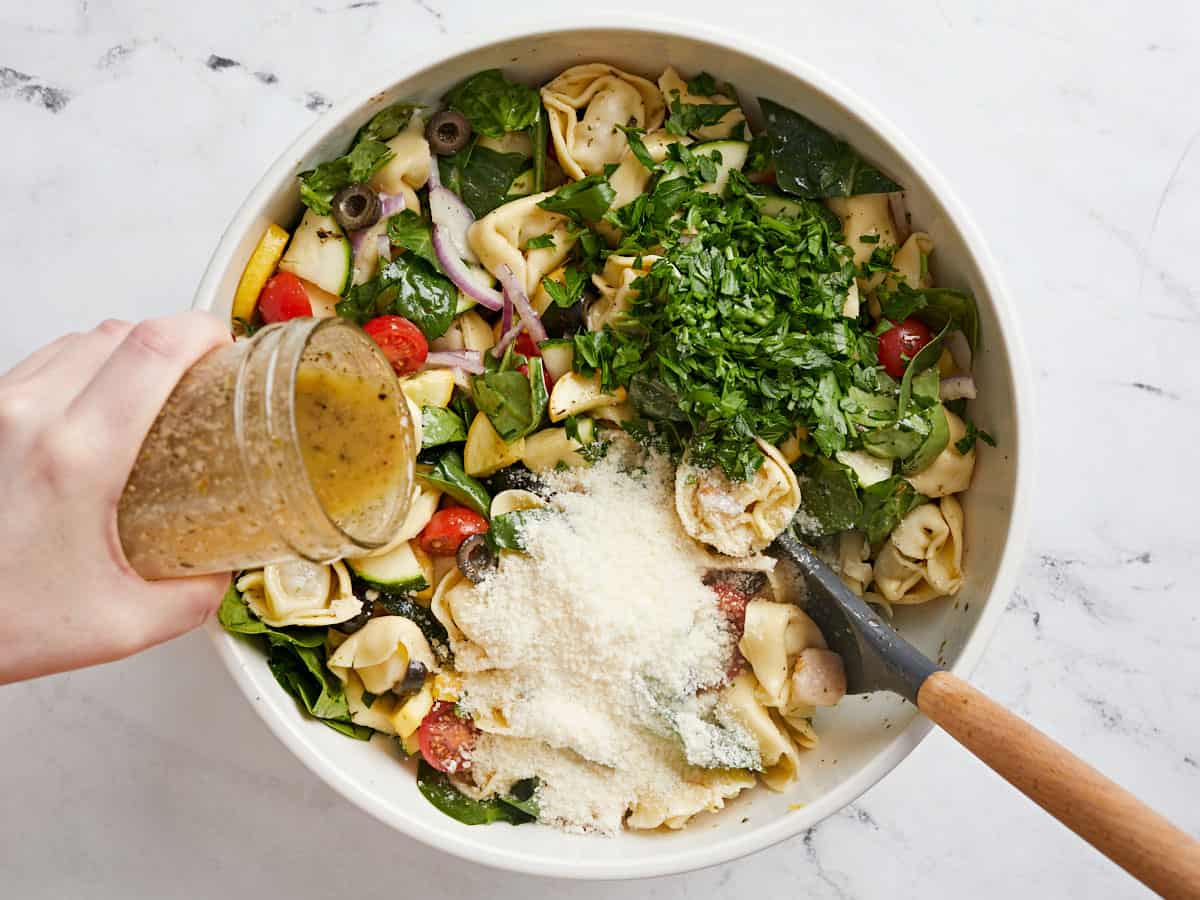 Chopped parsley and Parmesan added to the bowl with more dressing being drizzled over top.