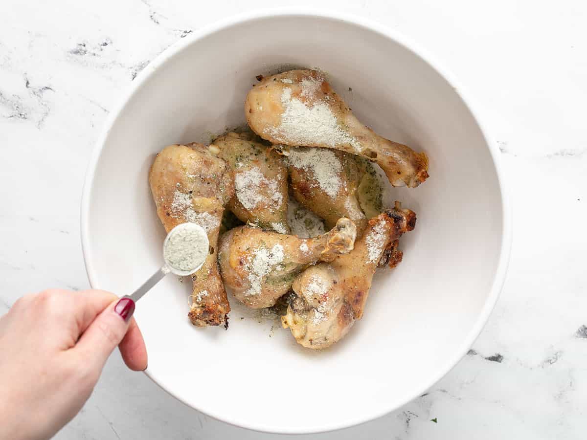 Ranch seasoning being sprinkled over the drumsticks.