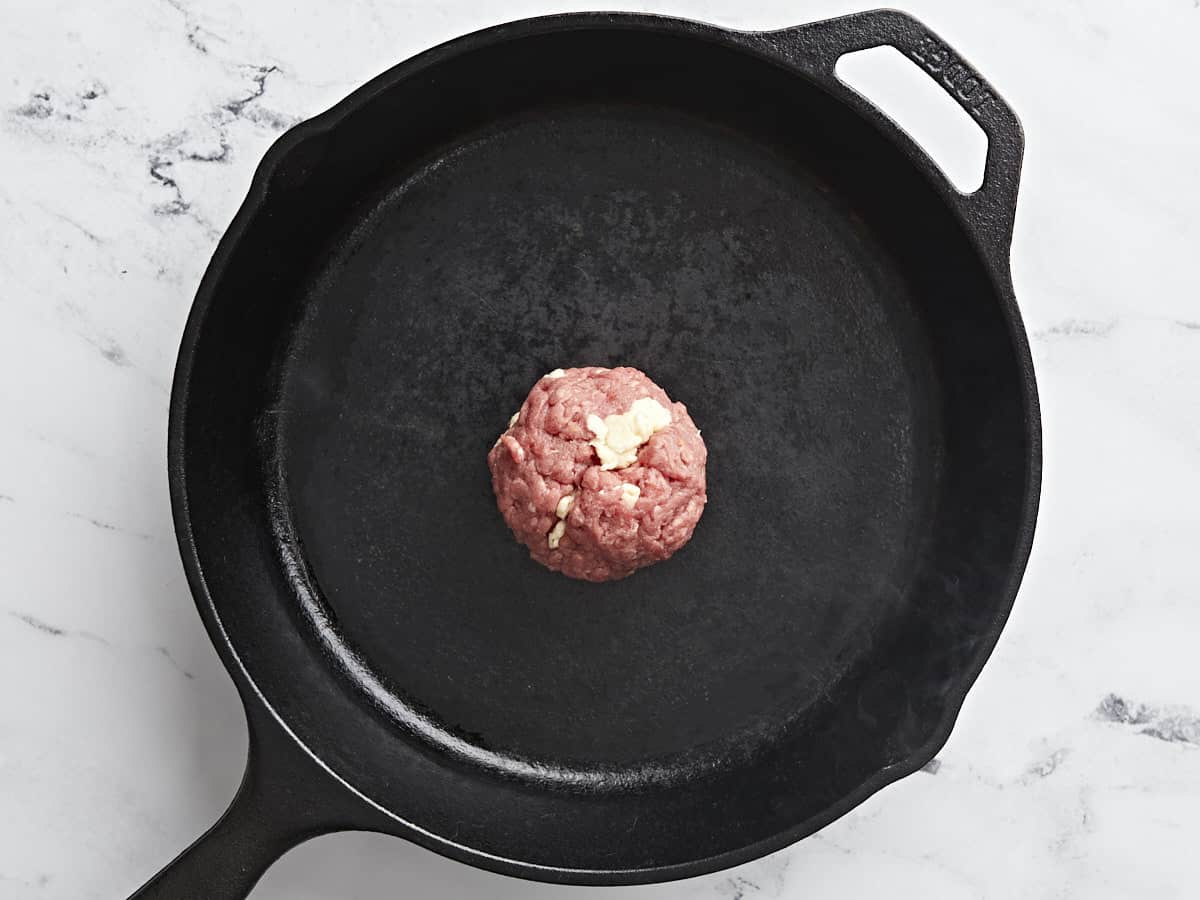 Overhead shot of ball of beef in a black cast iron pan.