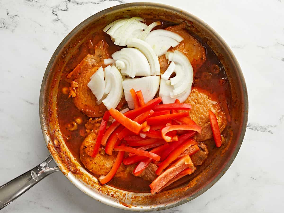 Onions and peppers added to the skillet.