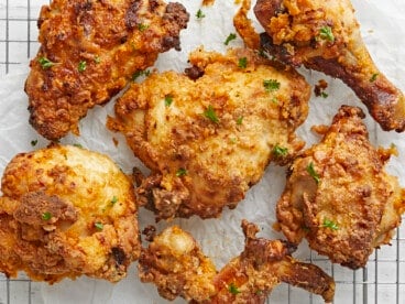 Overhead close up view of Air Fryer Fried Chicken on parchment paper and a cooling rack.