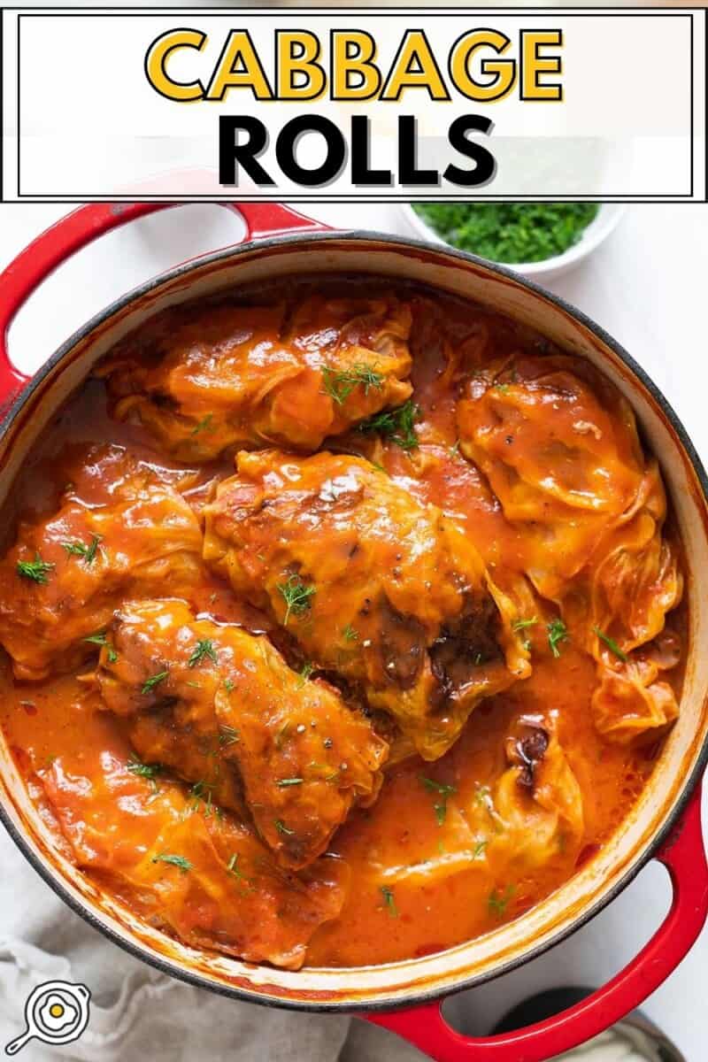 Cooked cabbage rolls baked in a dutch oven with tomato sauce and recipe title at the top.