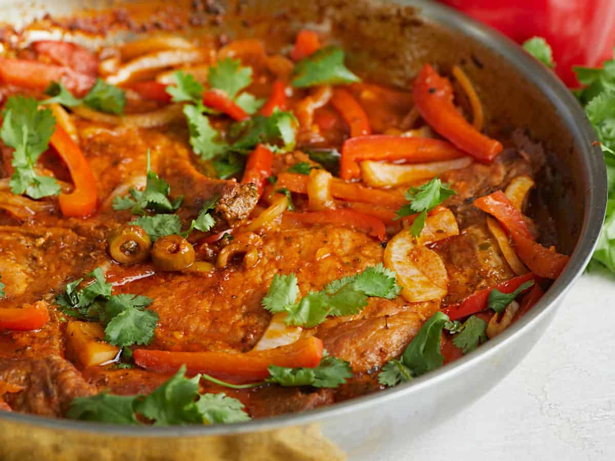 Close up side view of Chuletas Guisadas in a pan. 