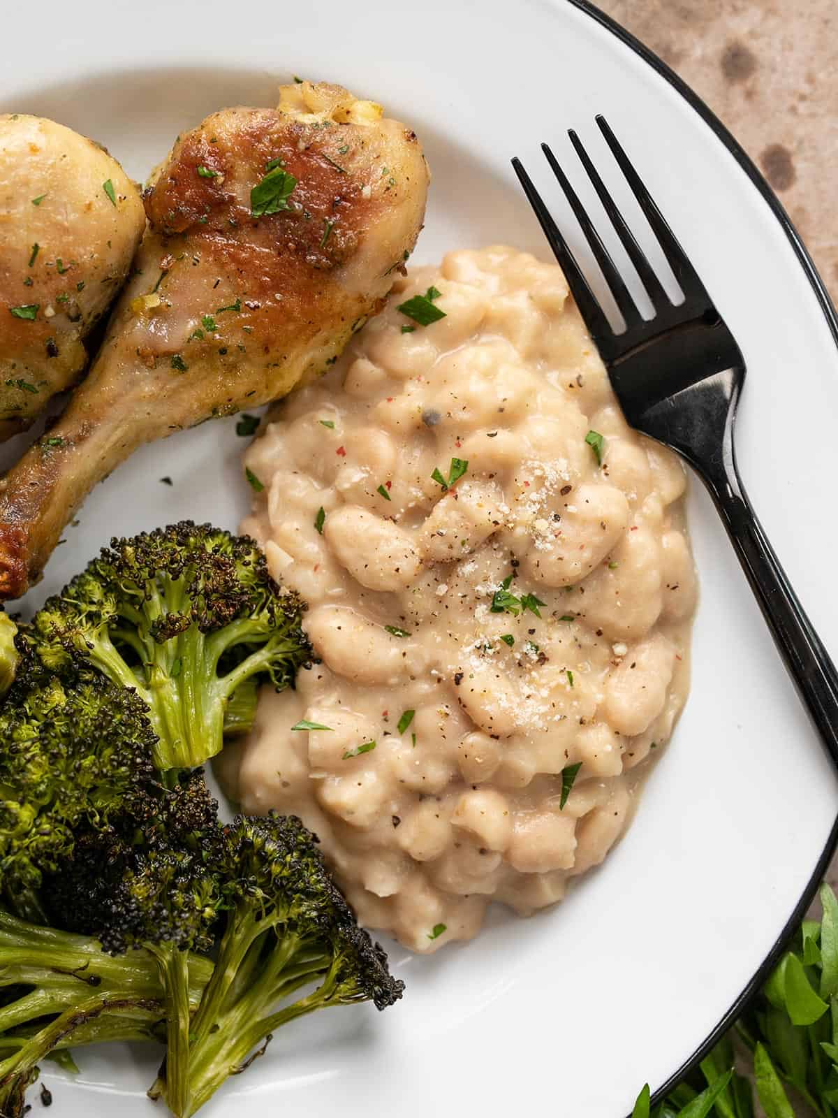 Overhead view of Parmesan beans on a plate with chicken and broccoli.