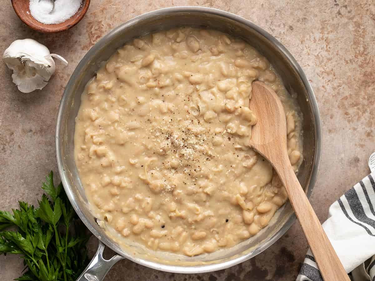 Finished beans in the skillet with a wooden spoon.