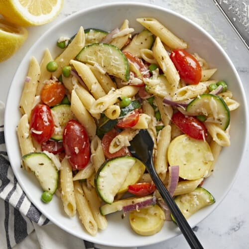 A bowl of pasta primavera with a fork in the center.