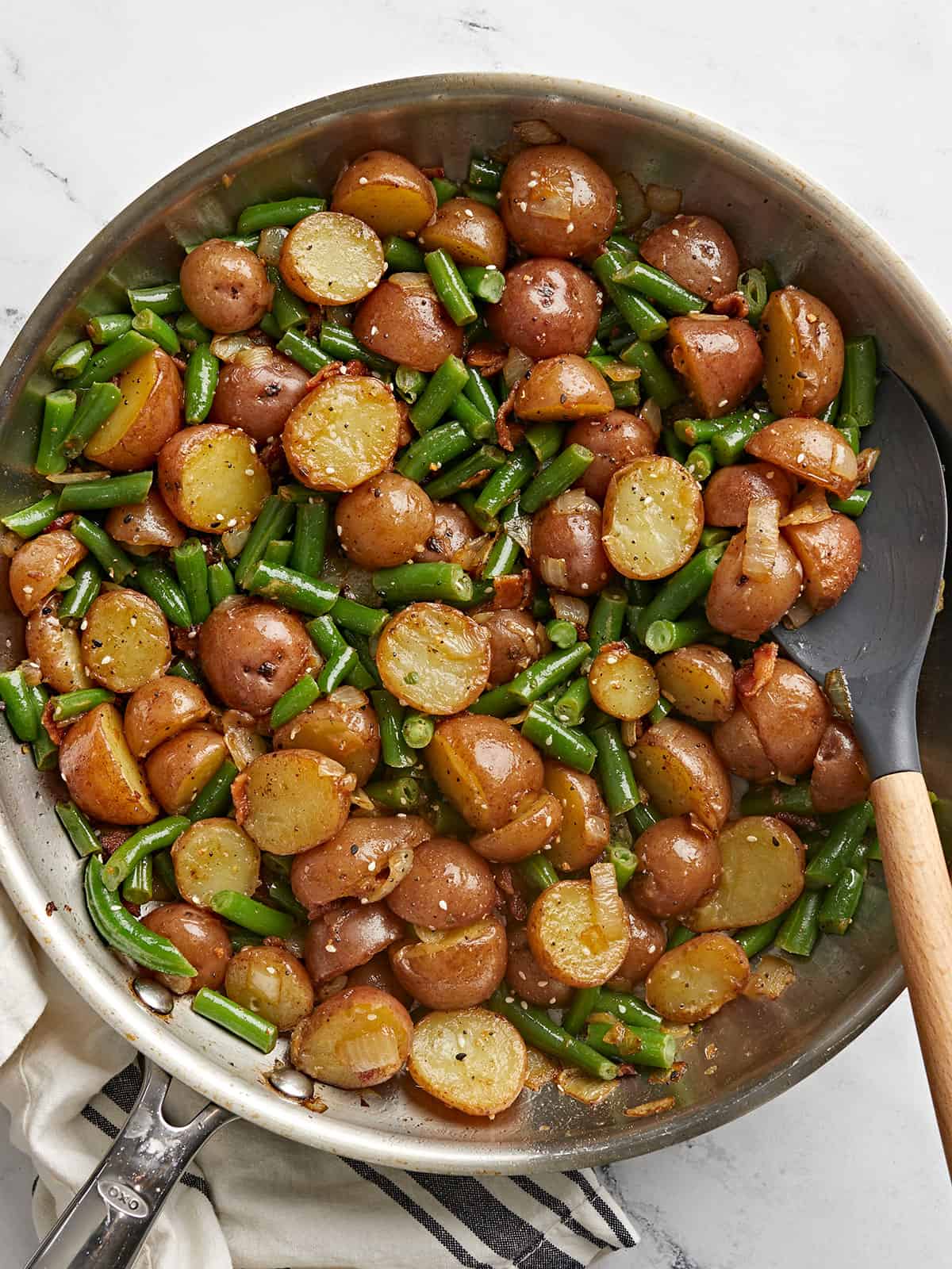 Overhead view of potato and green bean skillet with a spatula.