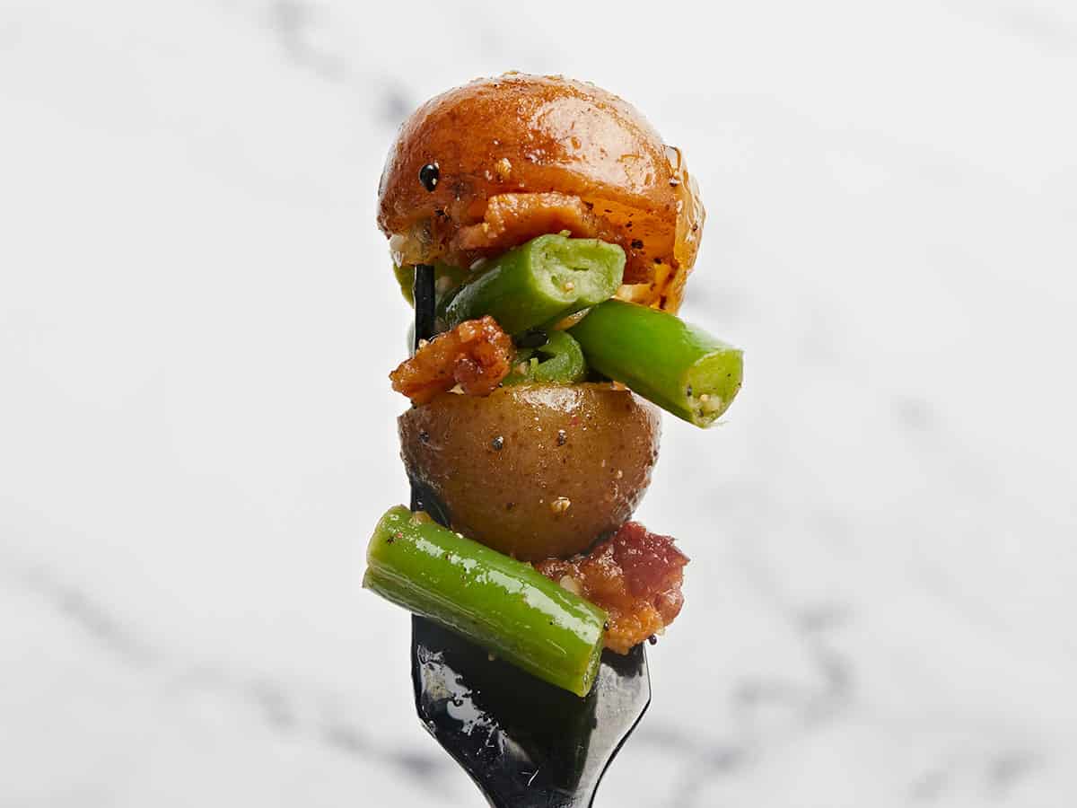 Potatoes, green beans, bacon, and onion on a fork close up. 