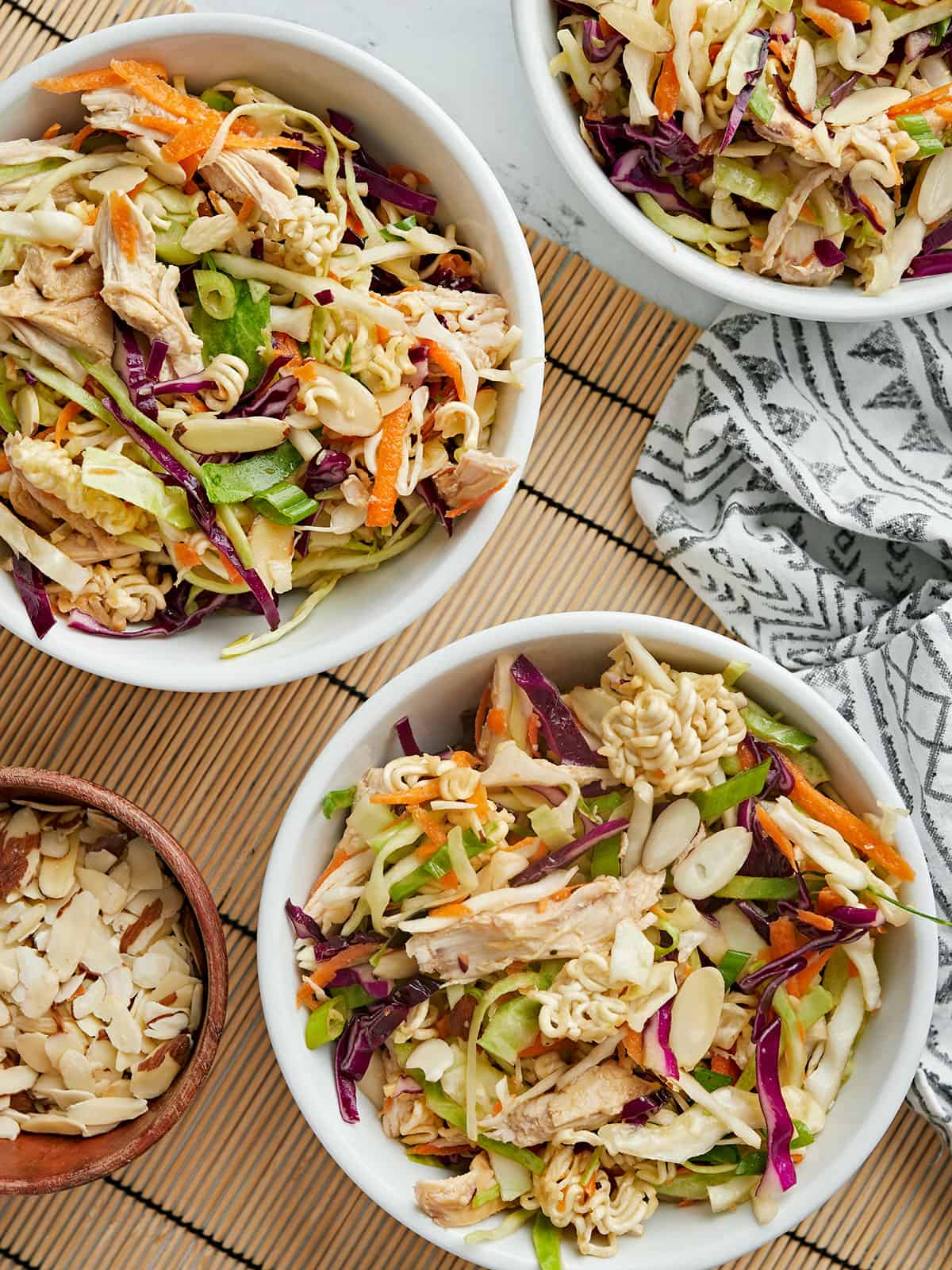 Overhead view of three bowls of ramen noodle salad.