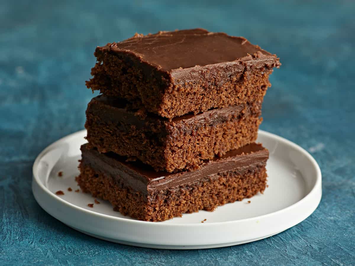 Three slices of chocolate cake on a plate, stacked.