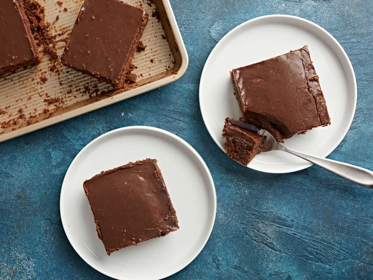 Two plates with slices of cake on them, one with a fork. 