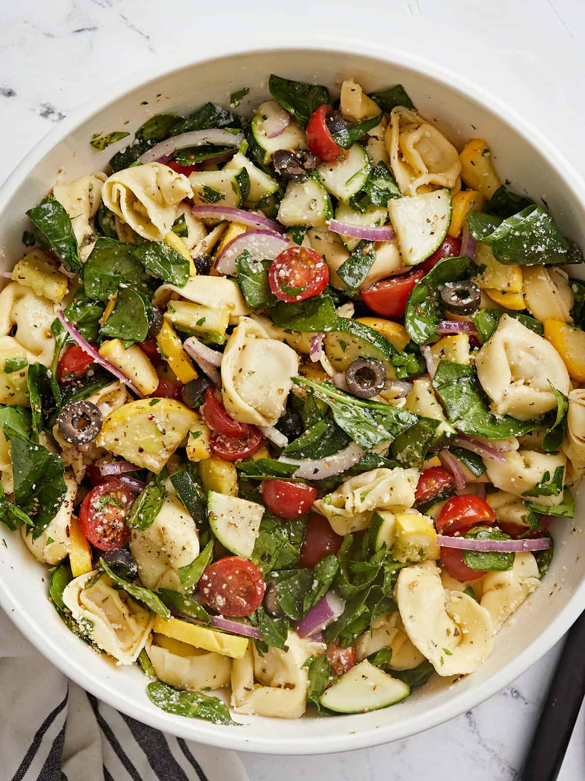 Overhead shot of tortellini salad in a white bowl.