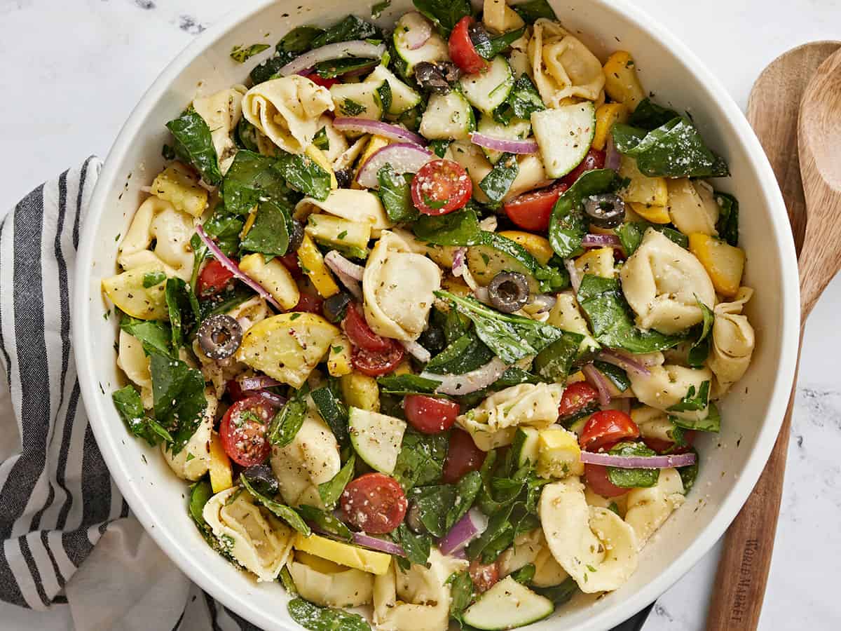 Overhead shot of tortellini salad in a white bowl.