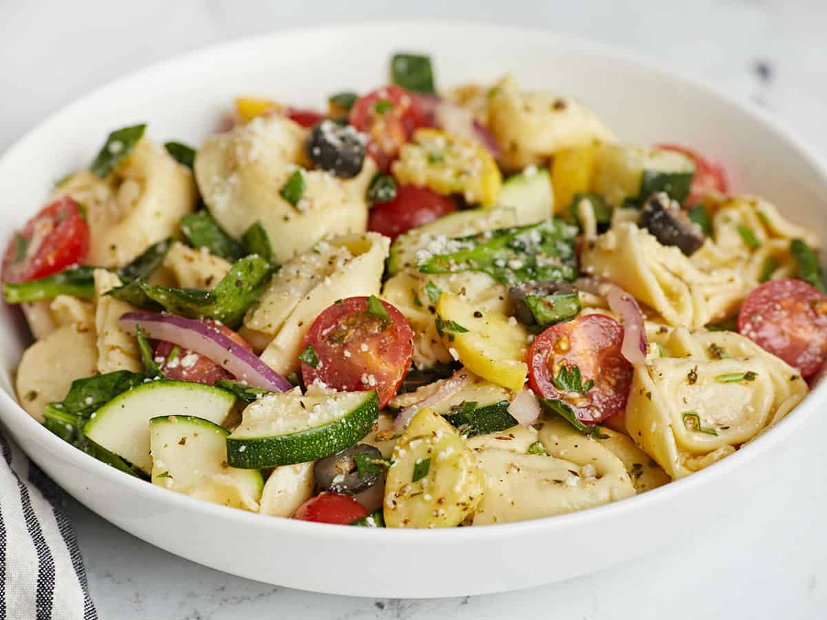 Side shot of tortellini salad in a white bowl.