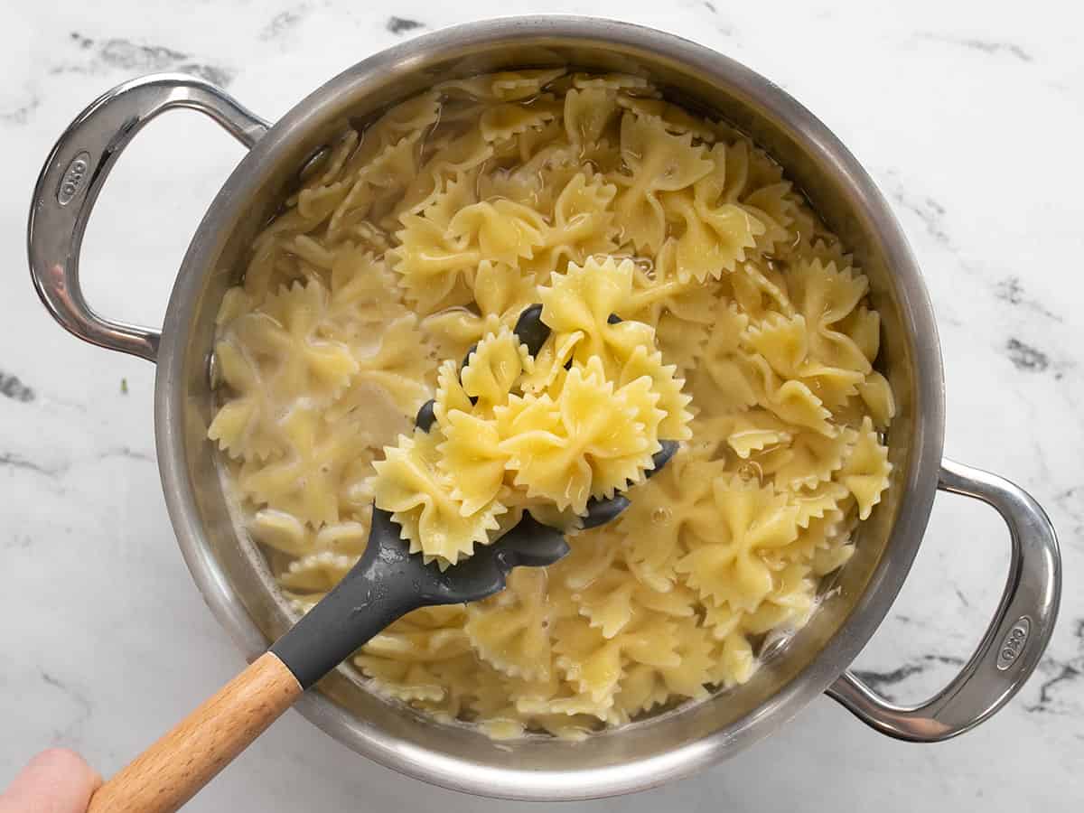Cooked bowtie pasta in the pot being lifted by a pasta fork.