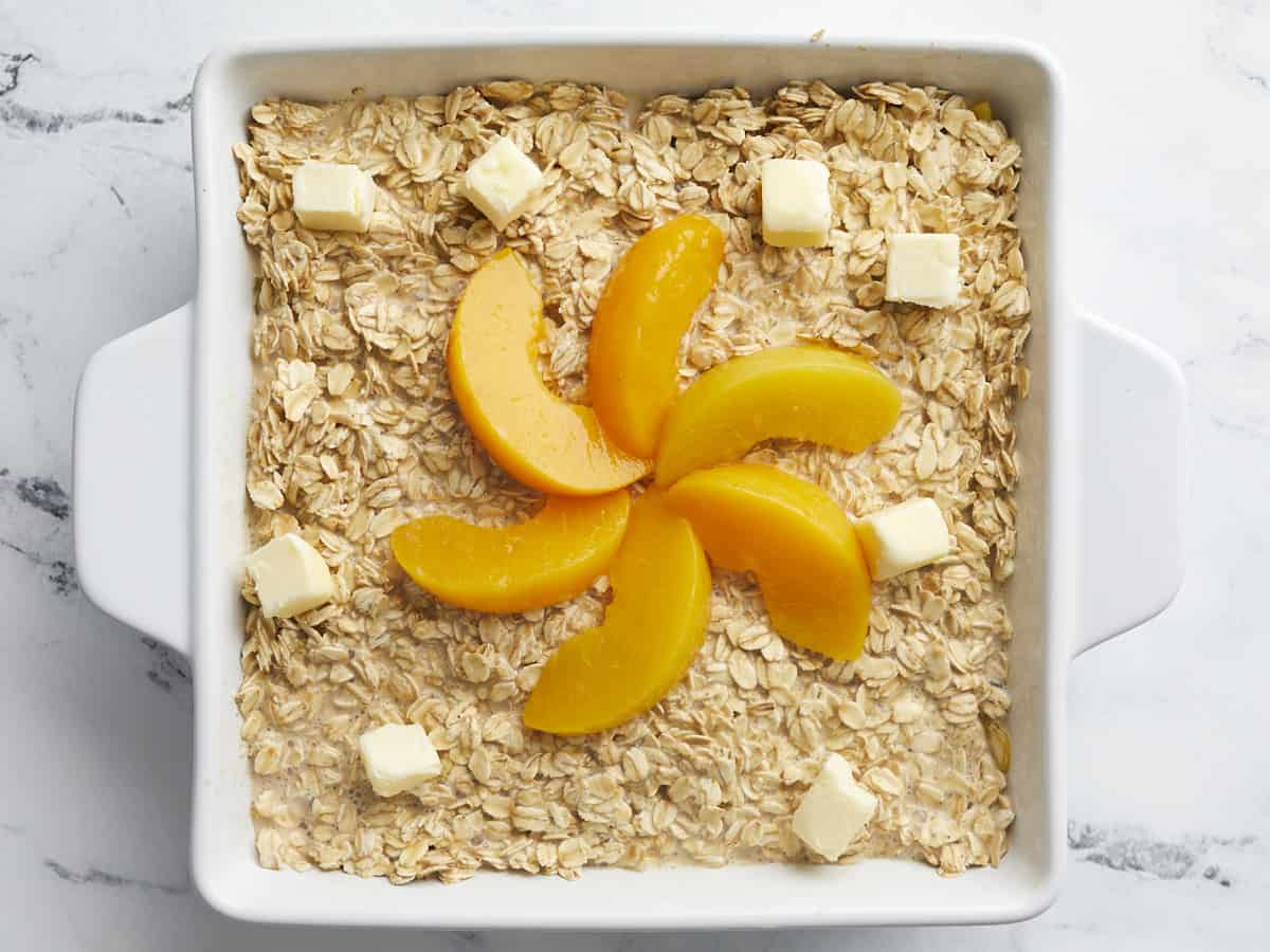 Overhead shot of raw Peach Baked Oatmeal in a white baking dish.