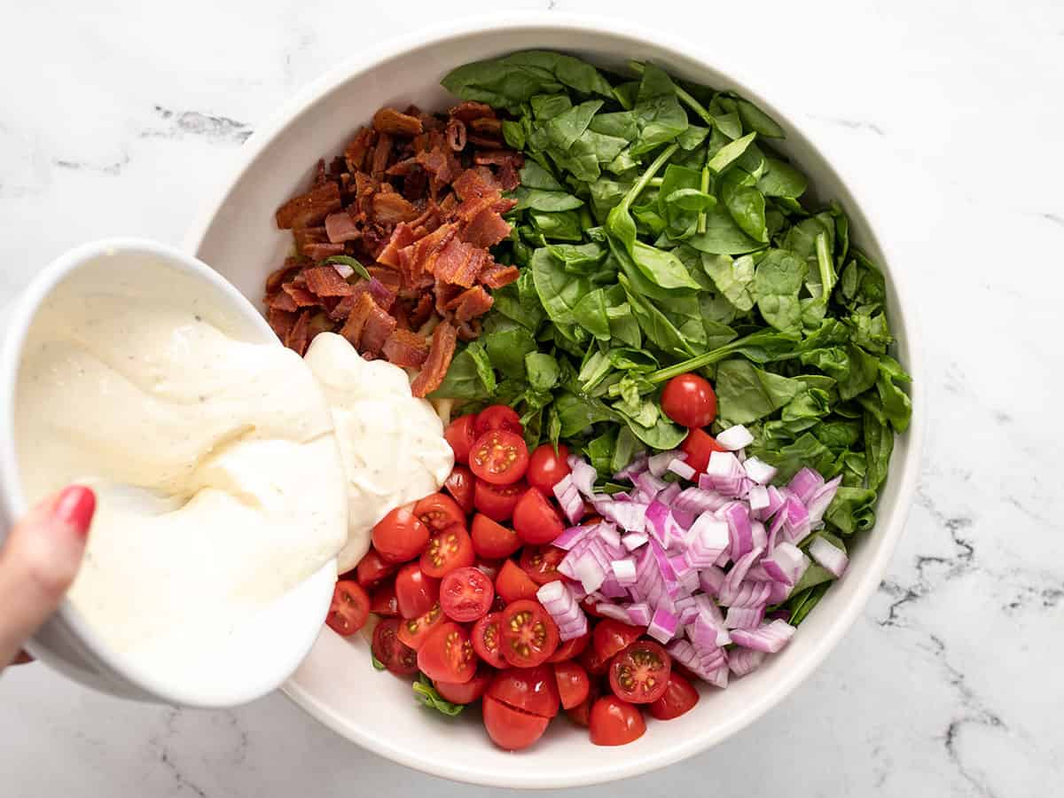 Ingredients for BLT pasta salad being combined in a bowl.