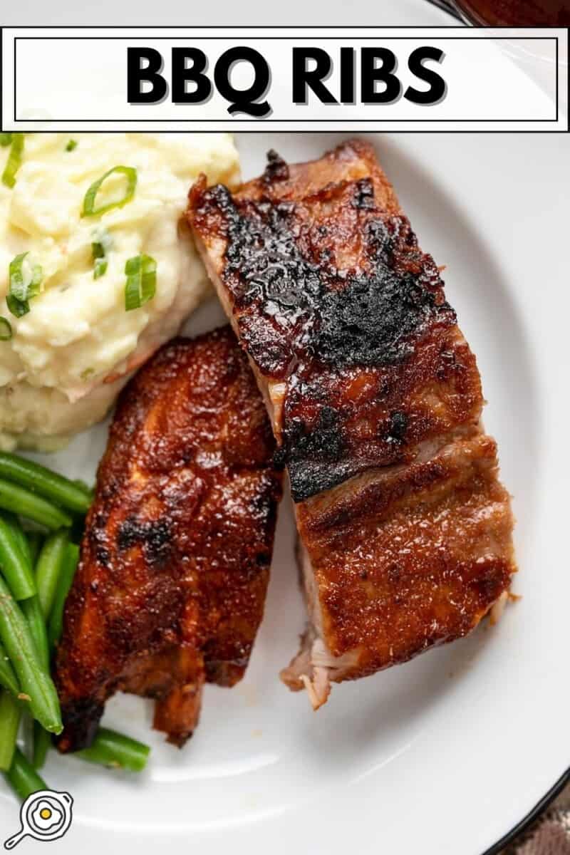 Cut ribs on a white plate with mashed potatoes and green beans.