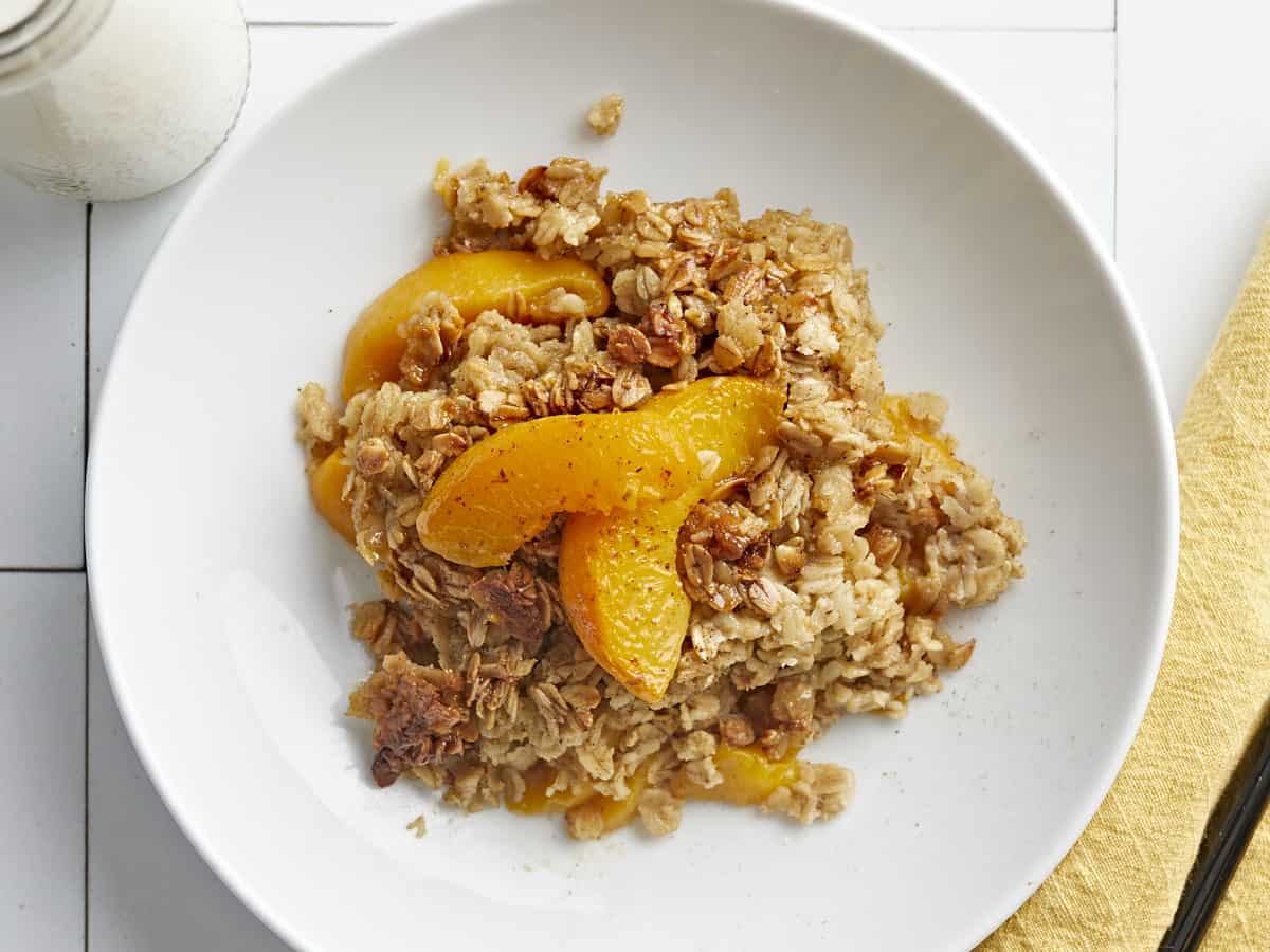 Overhead shot of Peach Baked Oatmeal in a white bowl with cream in it.