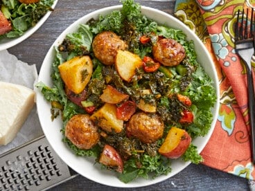 Overhead shot of Sausage Meatball and Kale Sheet Pan Meal in a white bowl.