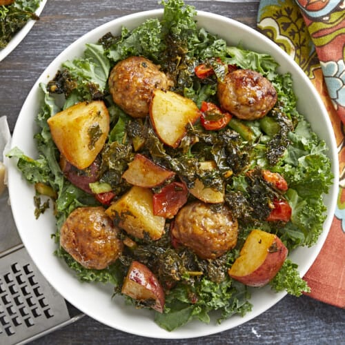 Overhead shot of Sausage Meatball and Kale Sheet Pan Meal in a white bowl.