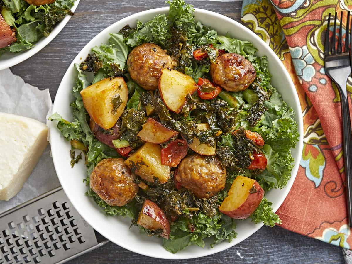 Overhead shot of Sausage Meatball and Kale Sheet Pan Meal in a white bowl.