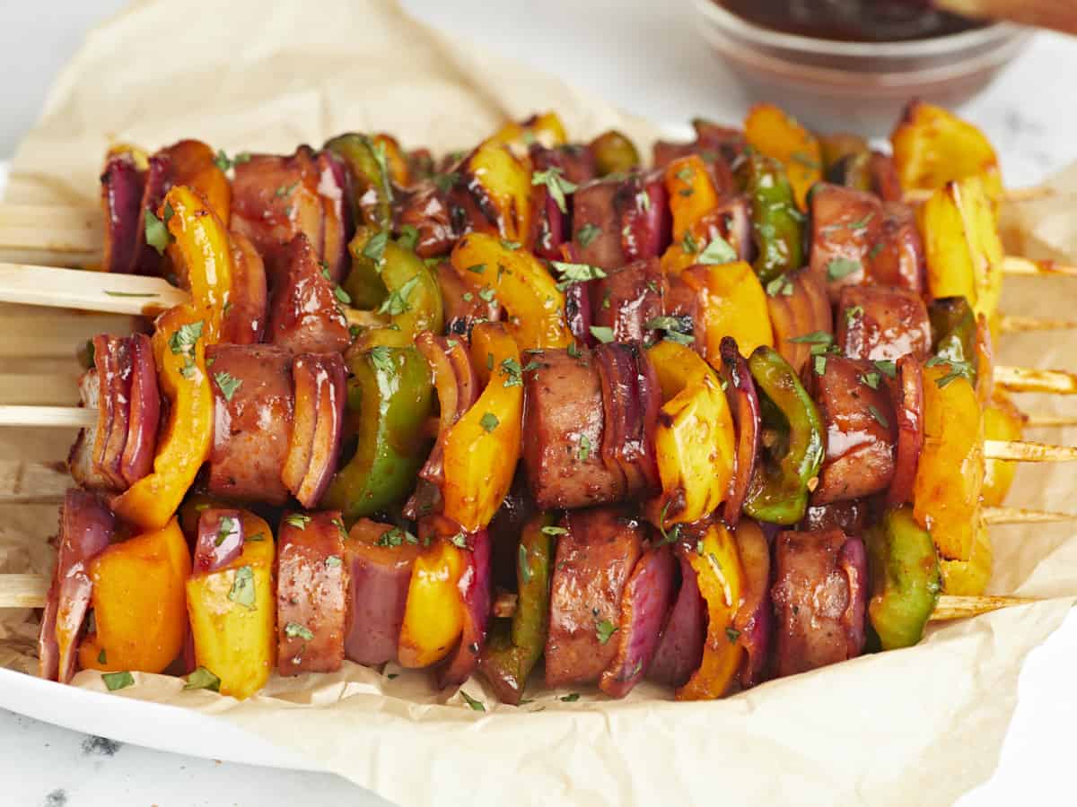 Side view of sausage kebabs on a serving platter with parchment paper.