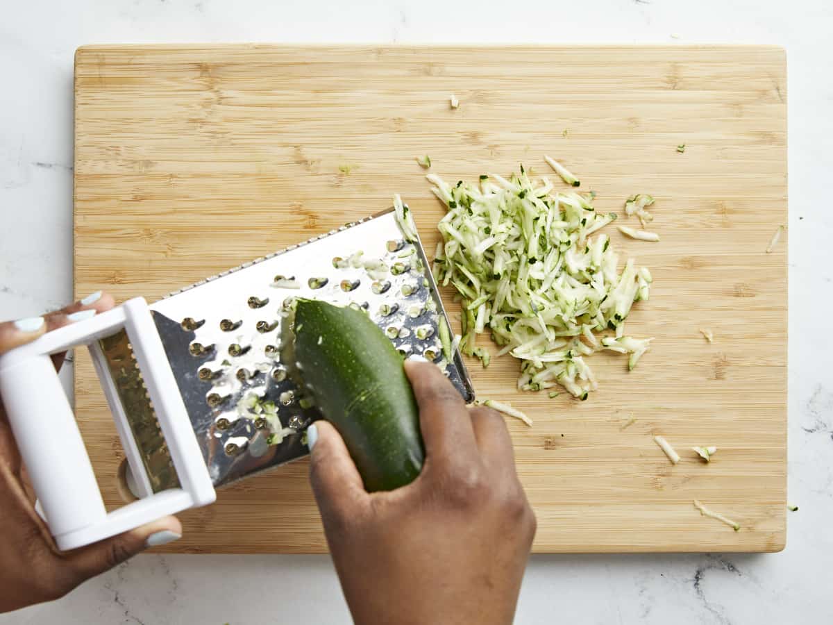 Shredding Zucchini with a box grater on a cutting board