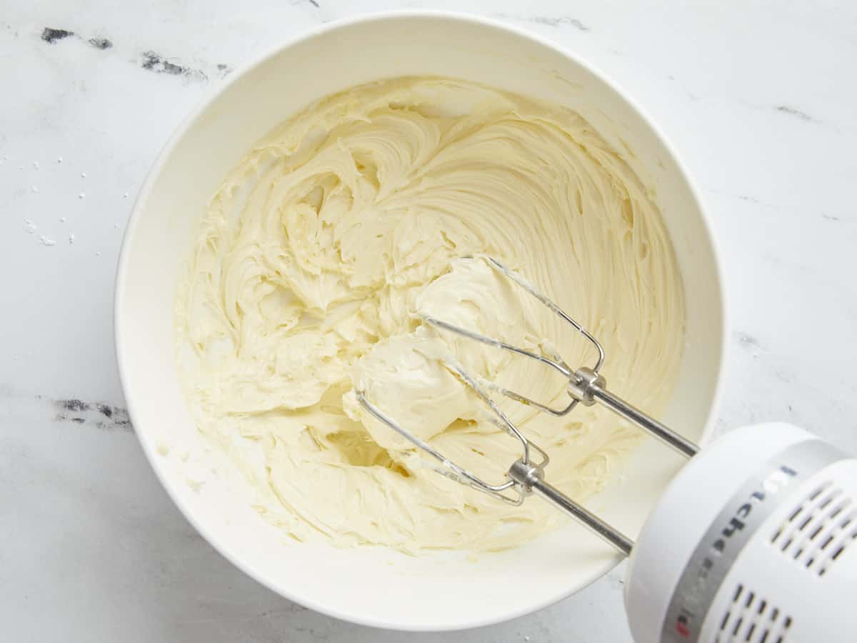 Overhead shot of filling mixed with a hand beater in a shite bowl.