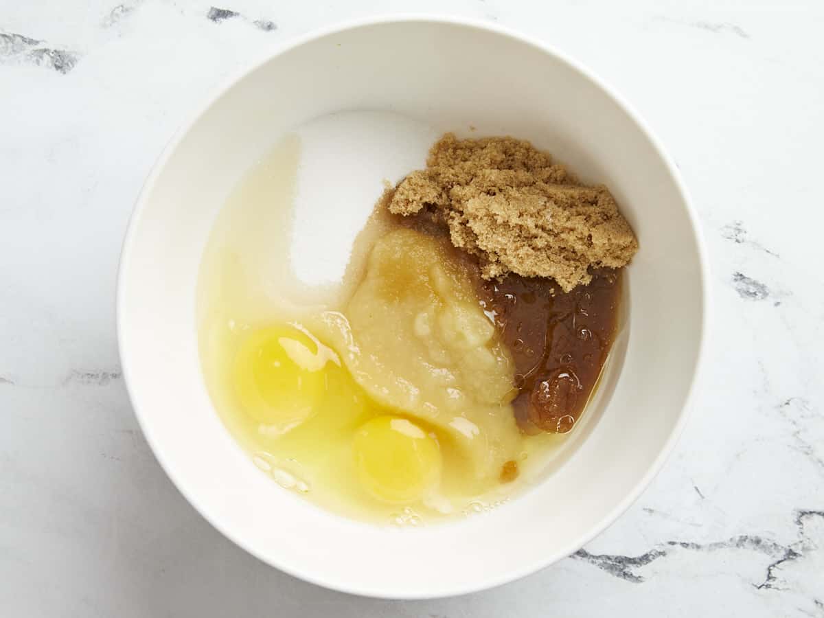 Wet ingredients for zucchini muffins in a white bowl.