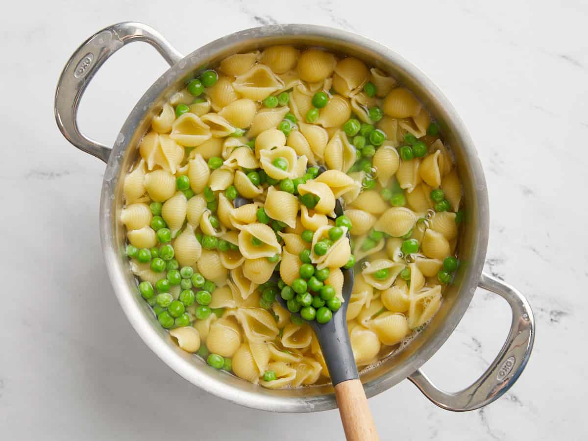 Boiled pasta and peas in a pot full of water.