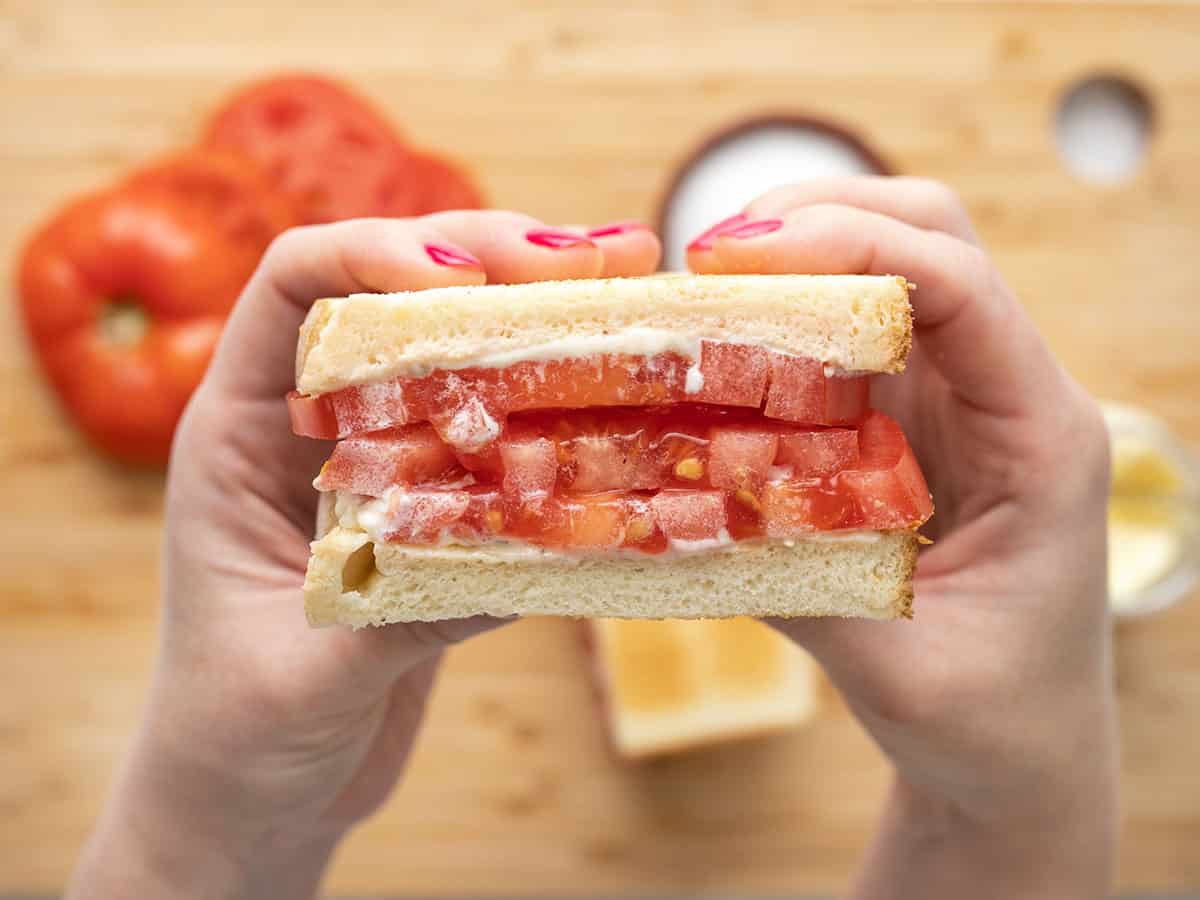 Sliced tomato sandwich held close to the camera.