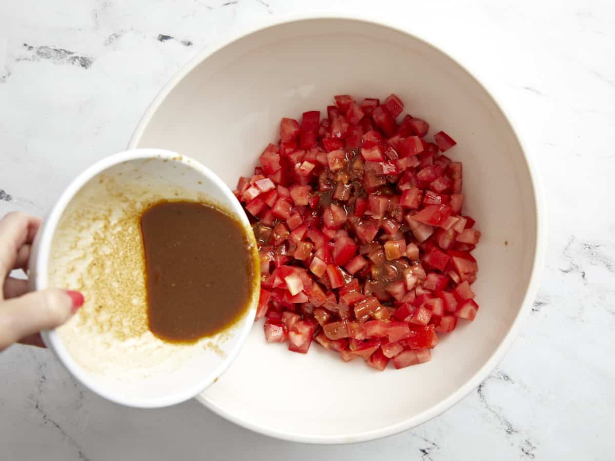 Dressing being poured over tomatoes.