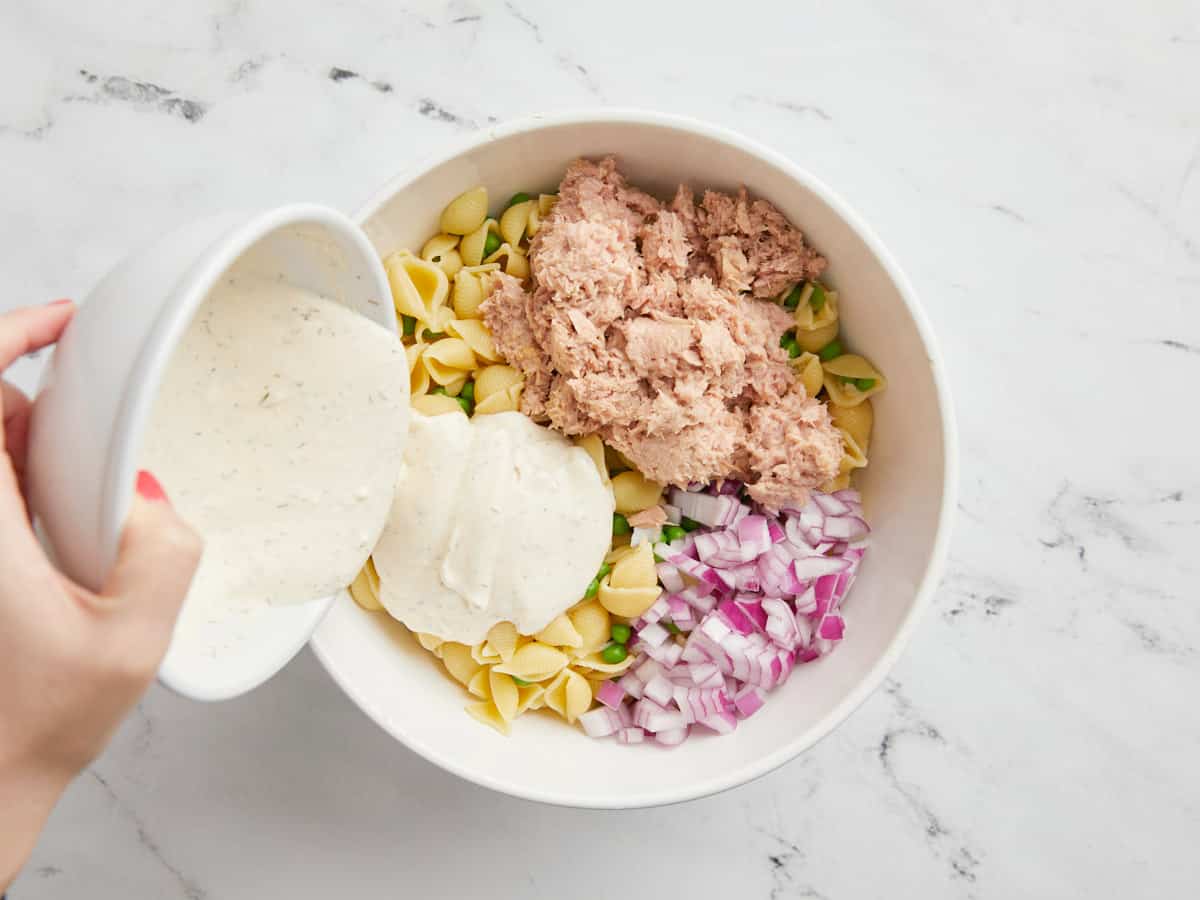 Ingredients for tuna pasta salad being combined in a bowl.