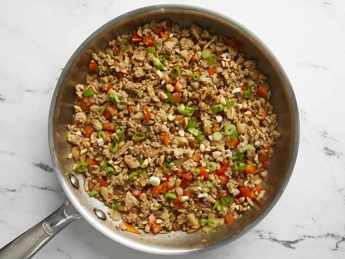 Finished chicken and vegetables with green onions and chopped peanuts sprinkled on top.