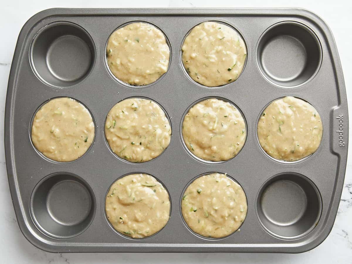 Zucchini muffin batter added to nonstick muffin pan.
