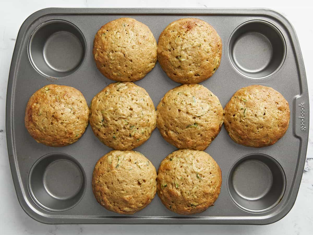 Overhead view of baked zucchini muffins in a muffin pan.