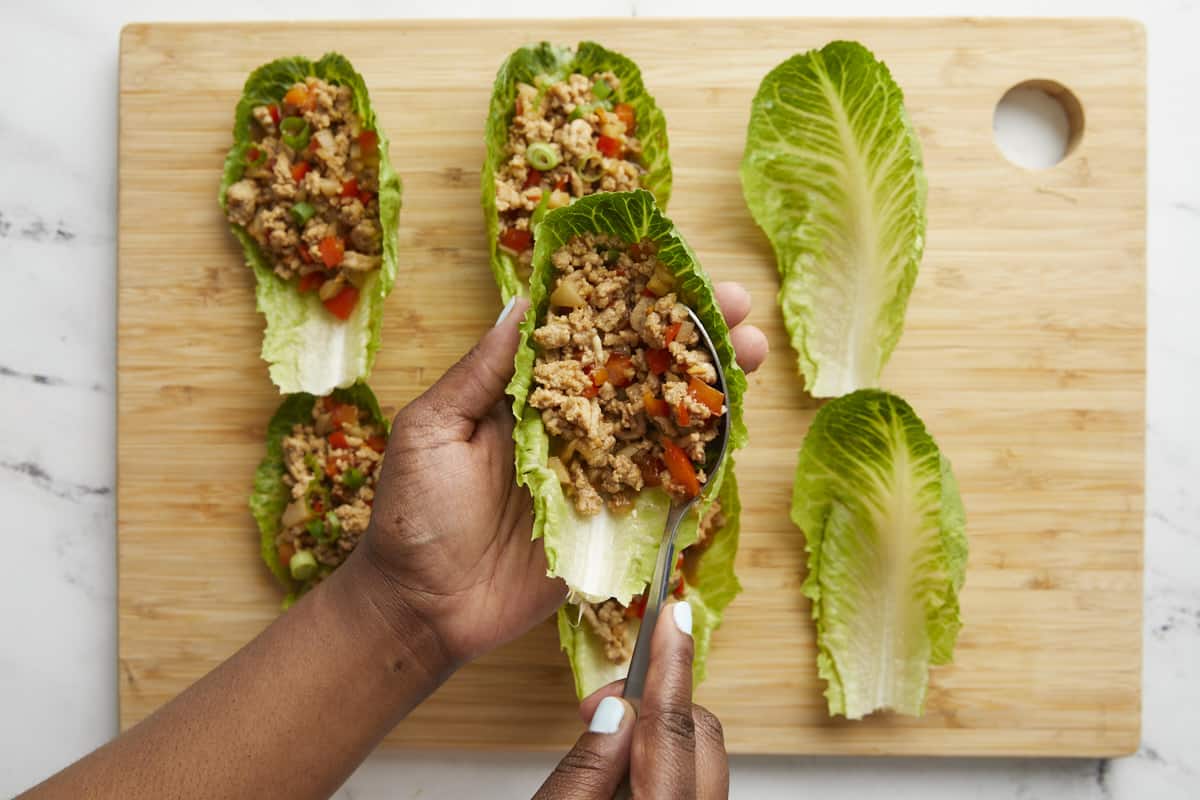 Chicken and vegetable filling being added to chicken lettuce wraps.