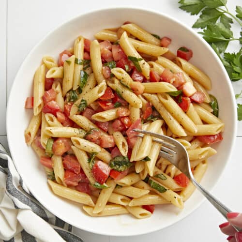 Overhead view of bruschetta pasta in a bowl with a fork.