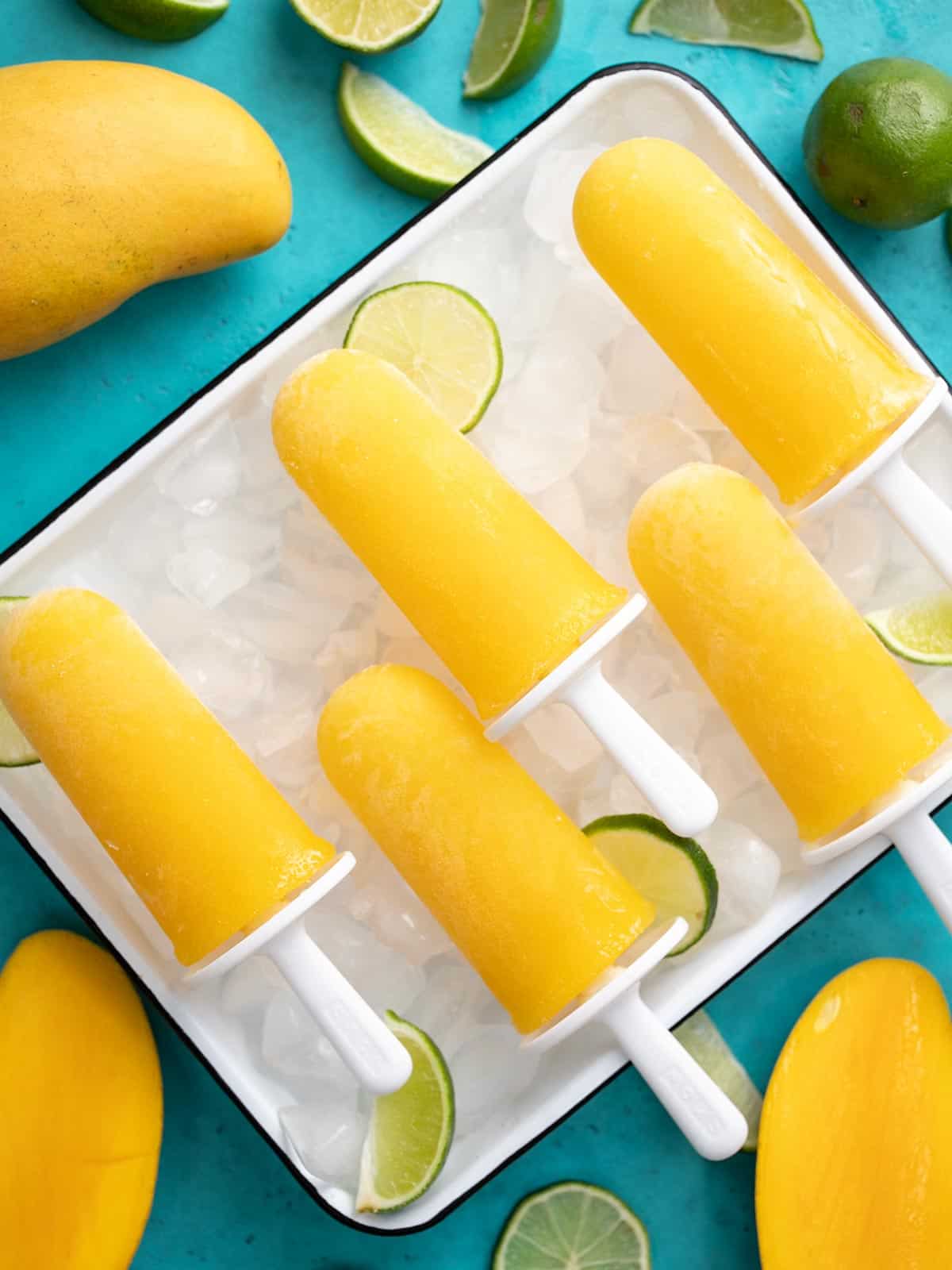 Overhead shot of four mango limbers on a sheet pan filled with ice.