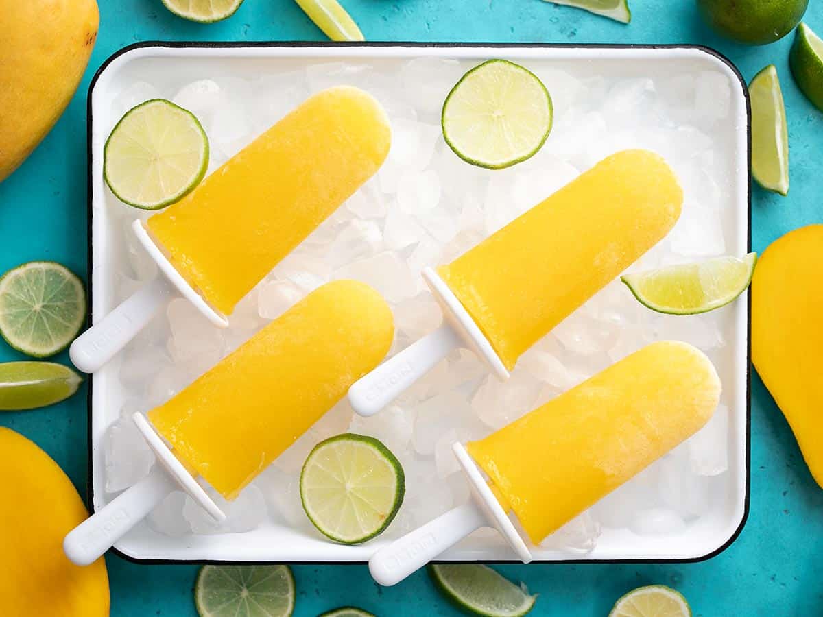 Overhead shot of four mango limbers on a sheet pan filled with ice.