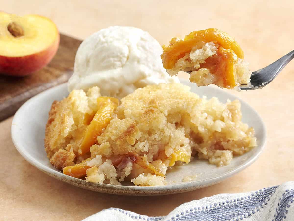 Side view of a plate of peach cobbler with a scoop of vanilla ice cream.