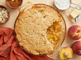 Overhead shot of peach cobbler with a scoop taken out in a glass pie plate.