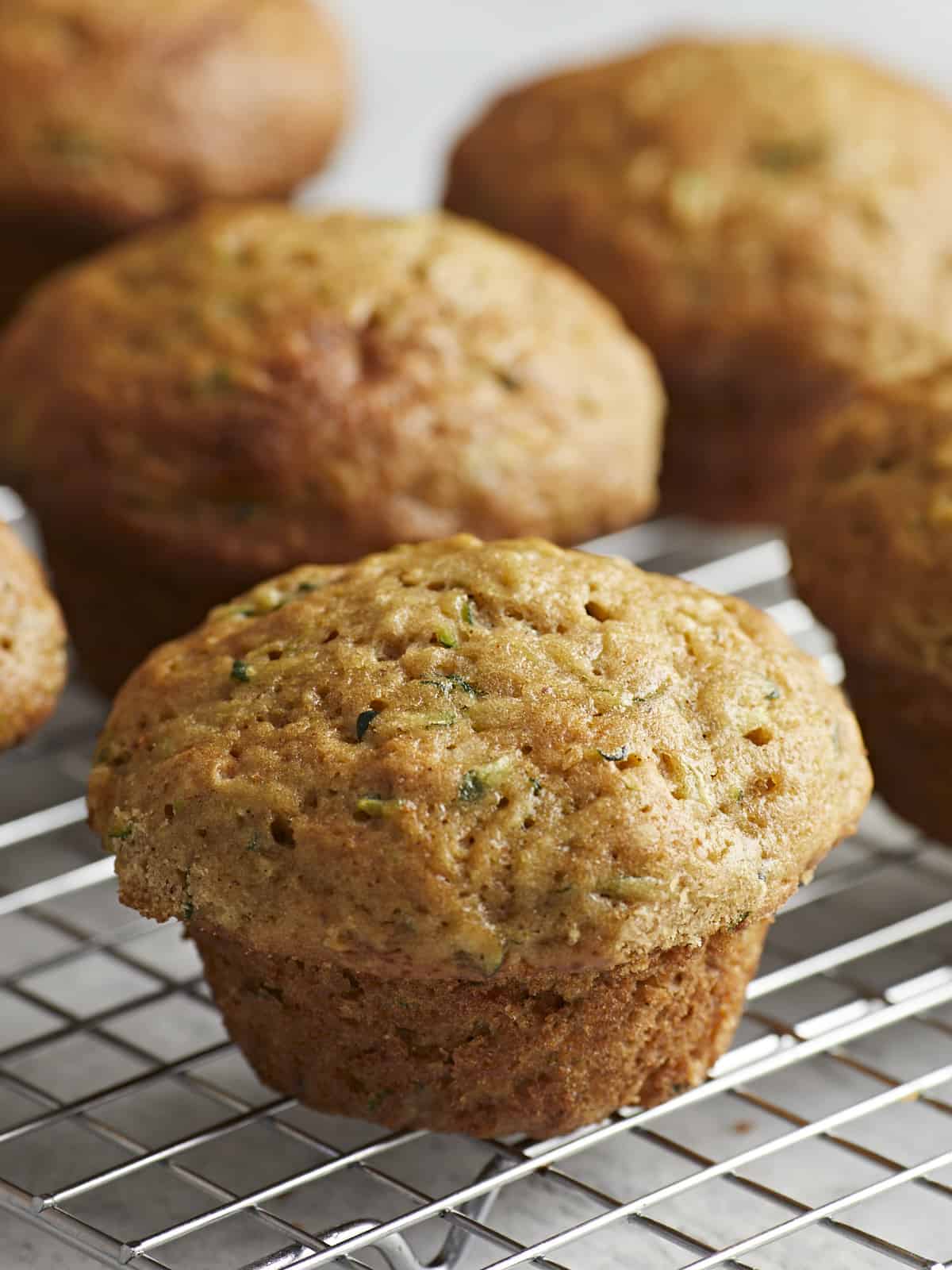 Close up side shot of Zucchini muffins on a wire rack.