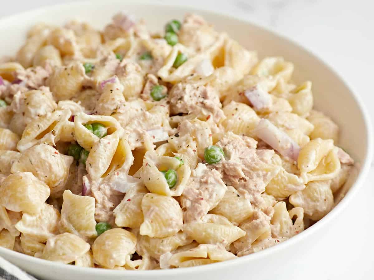 Close up side view of a bowl full of tuna pasta salad.