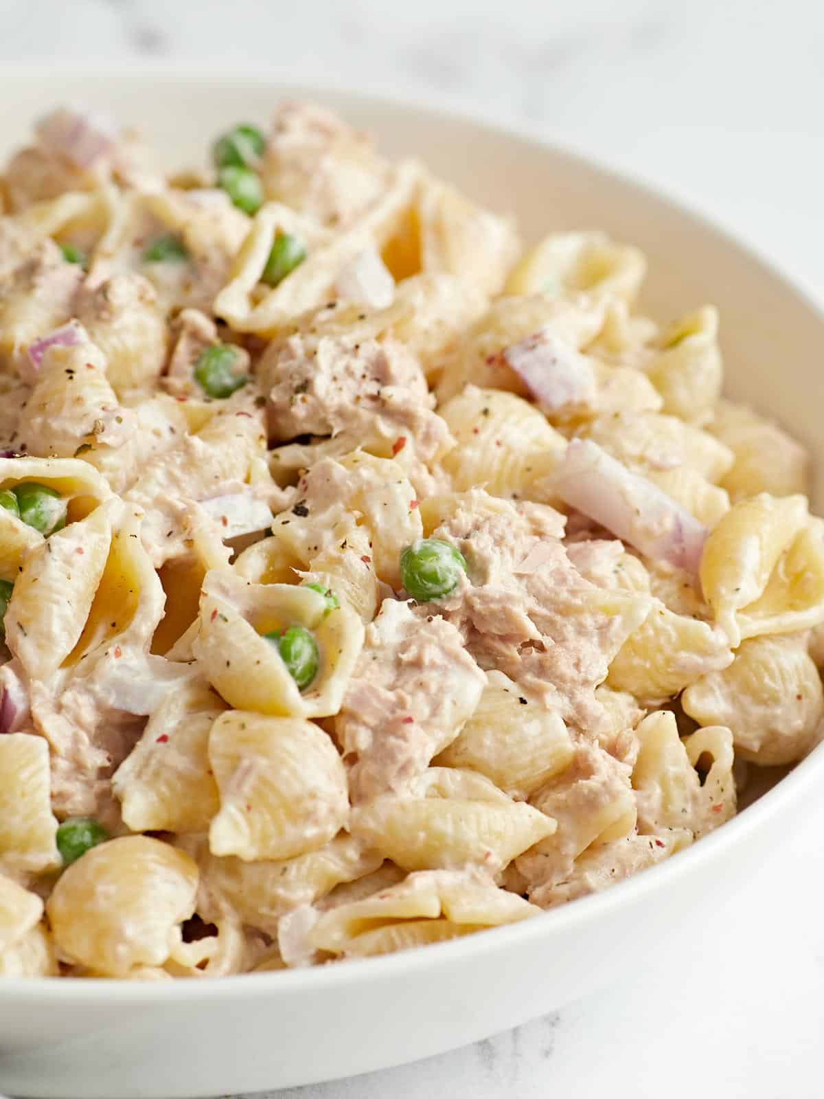 Close up side view of a bowl full of tuna pasta salad.