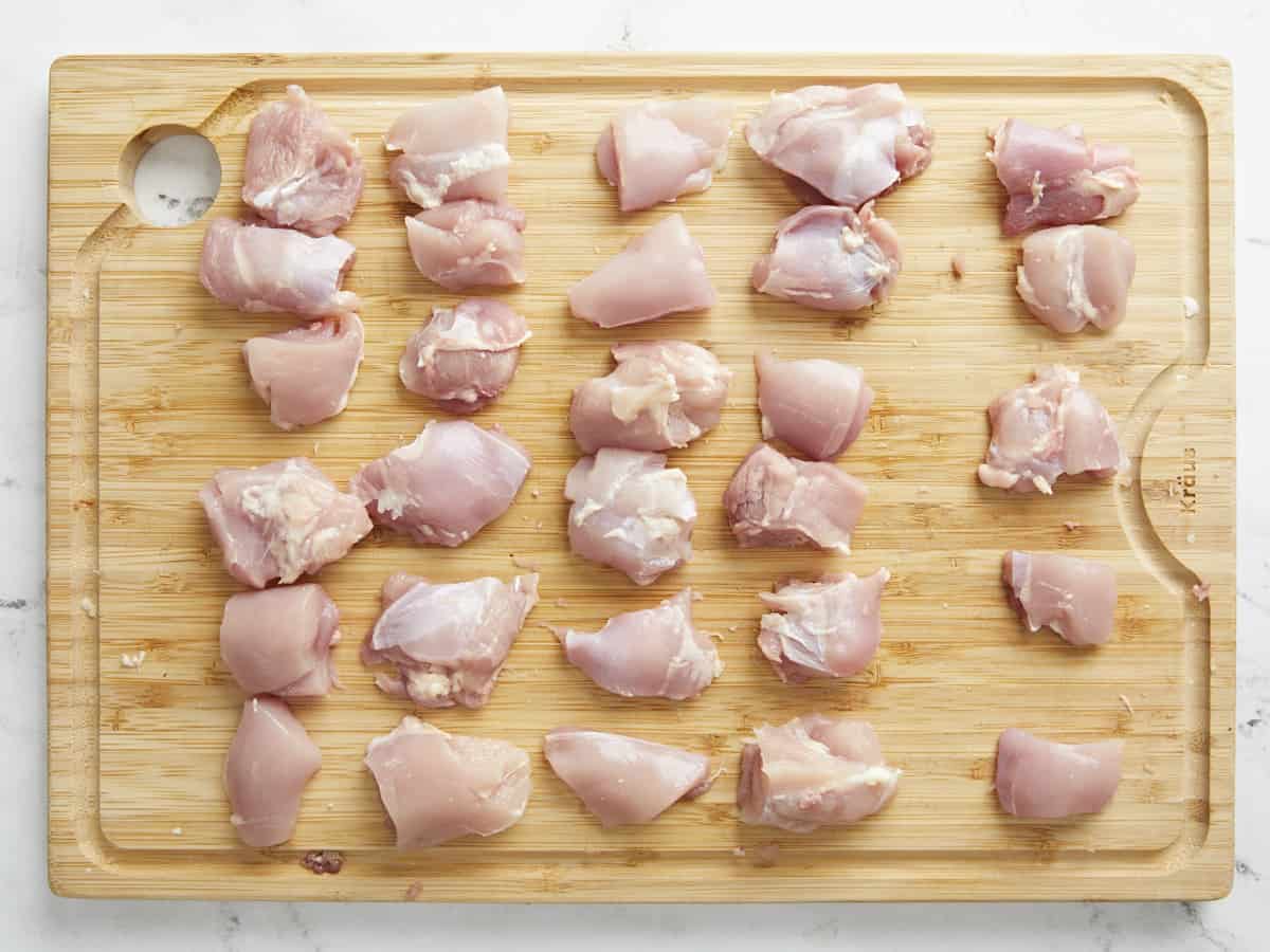 Overhead shot of cut chicken thighs on a wood cutting board.