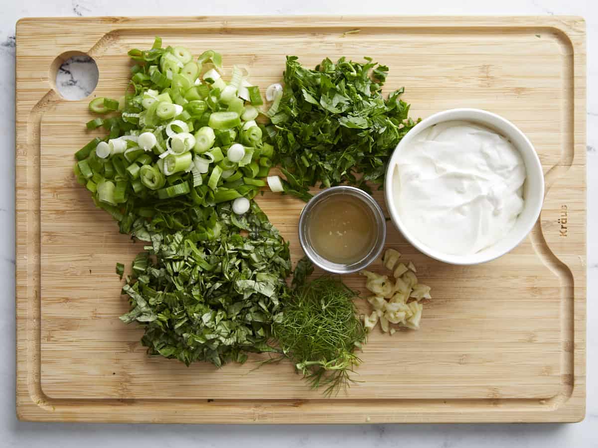 Overhead shot of Green Goddess Dressing ingredients on a wood cutting board.